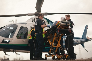 Life Flight team loads patient into helicopter from gurney in open field