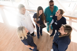 A group of students and professional huddle up for a quick meeting at Mercy Health