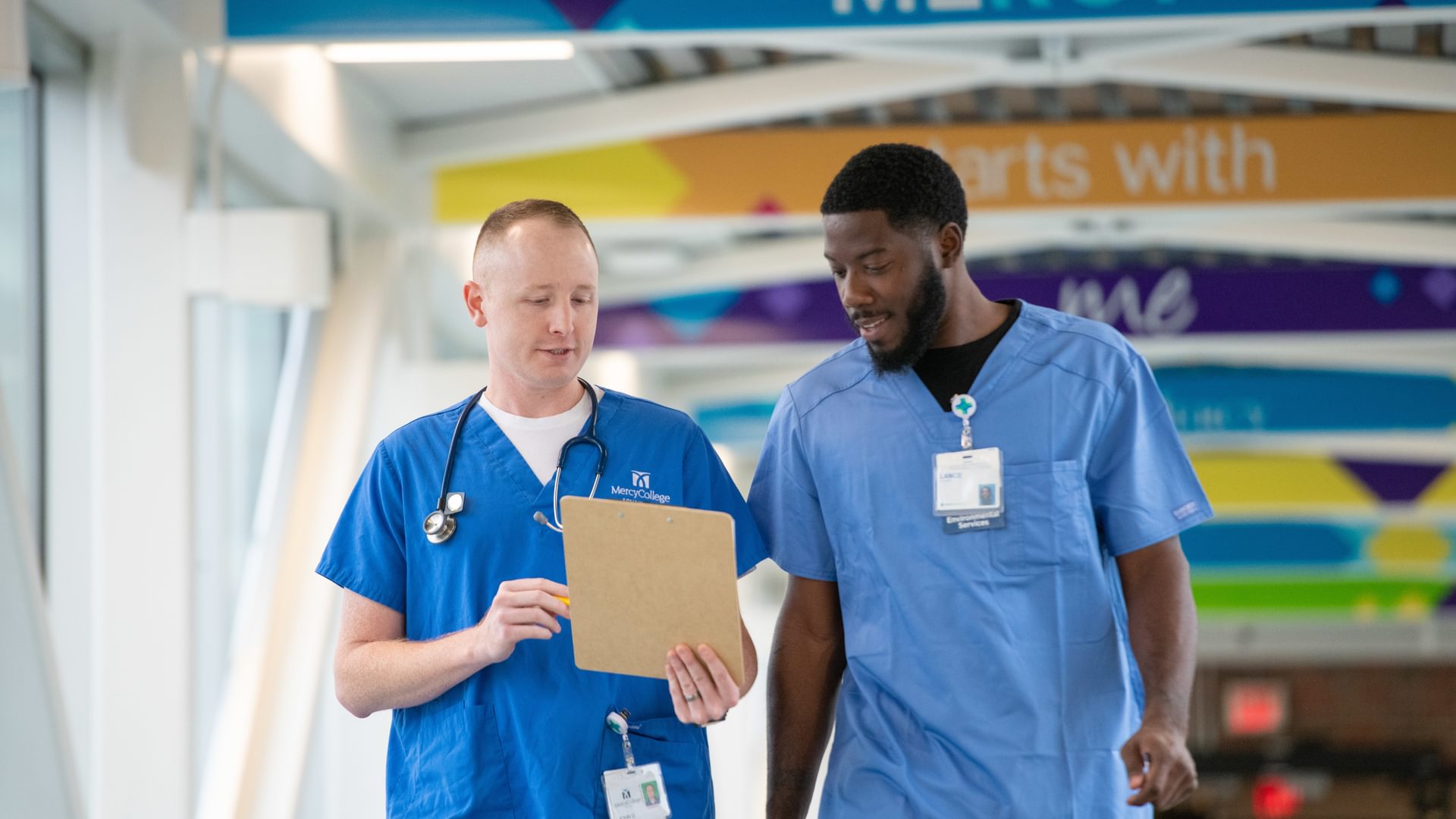 Two People in scrubs walking holding clipboard